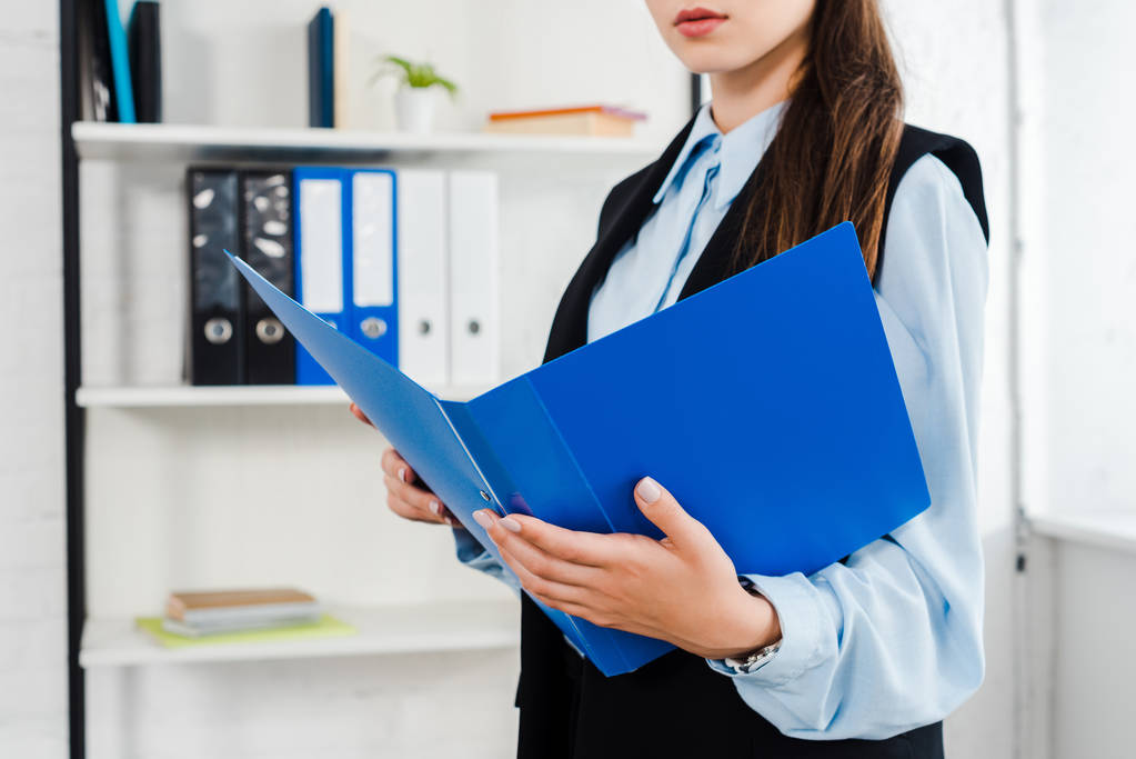 обрізаний знімок молодої бізнес-леді з папкою документів в сучасному офісі
 - Фото, зображення