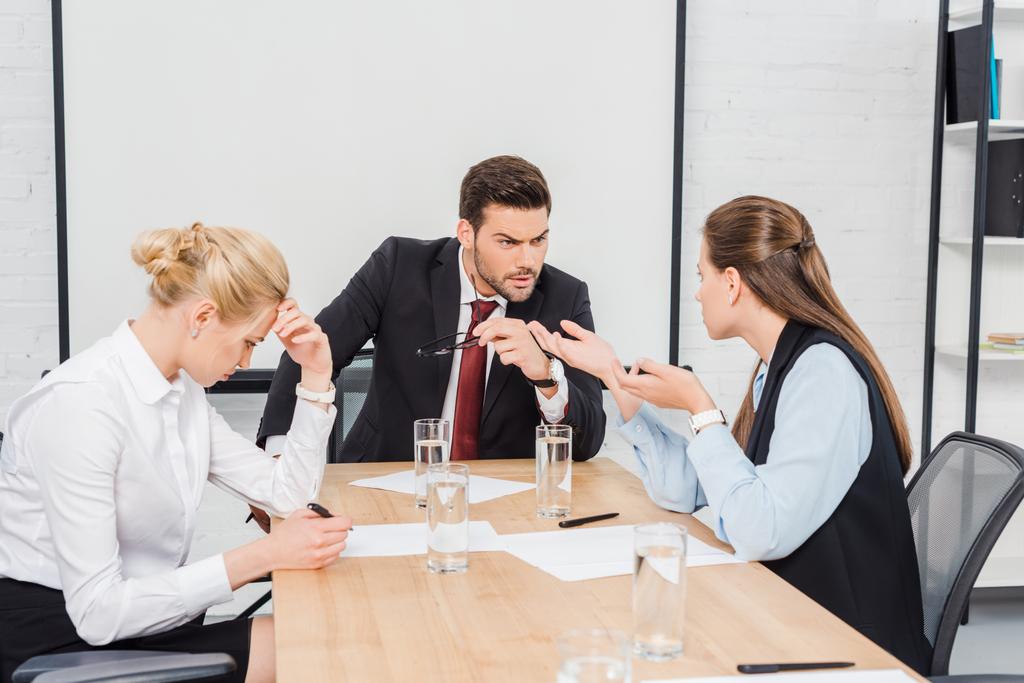 θυμωμένος αφεντικό μιλάει με τους συναδέλφους του γυναικείου στο σύγχρονο γραφείο - Φωτογραφία, εικόνα