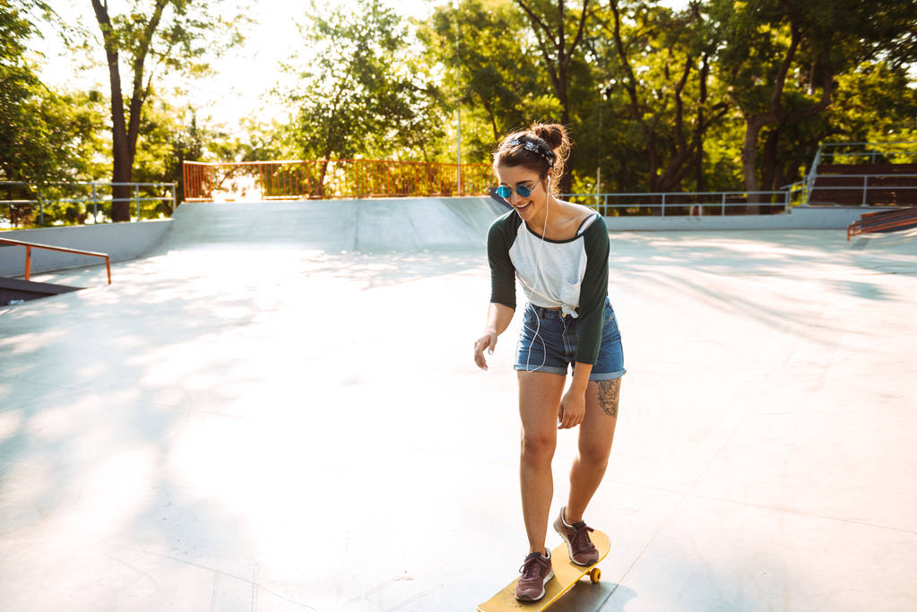 Foto van gelukkig vrolijke jongedame buiten wandelen met skateboard. - Foto, afbeelding