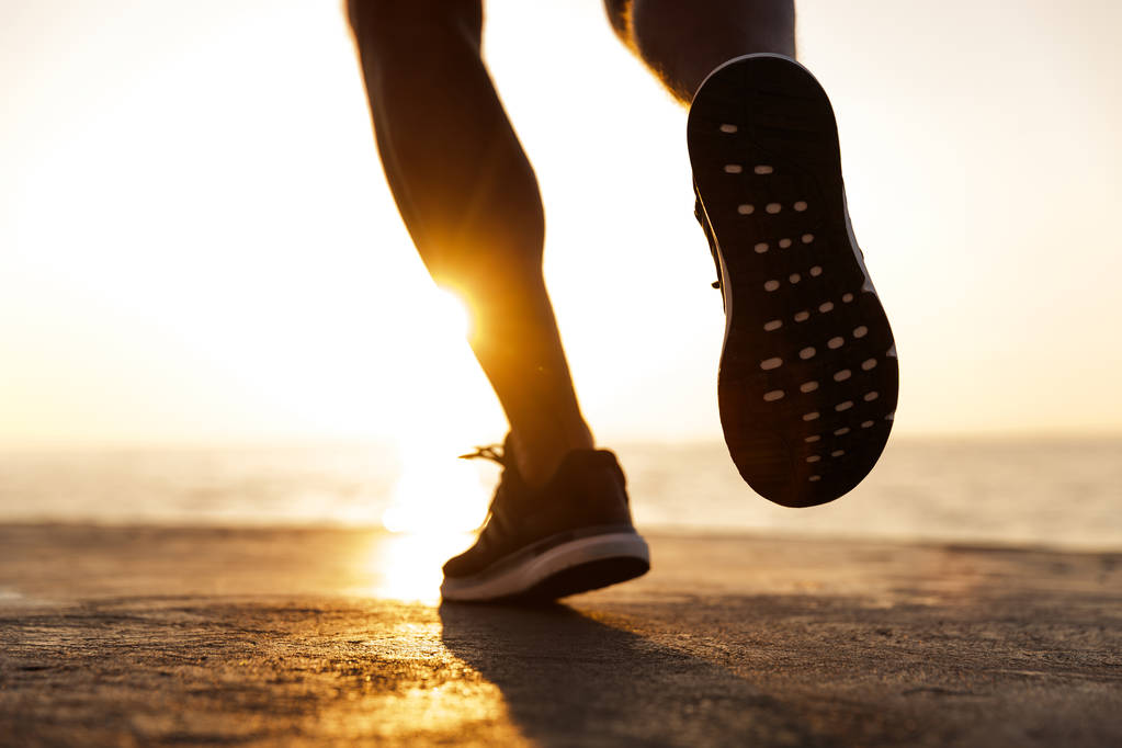 Вид сзади мужских кроссовок, бегающих по пляжу
 - Фото, изображение