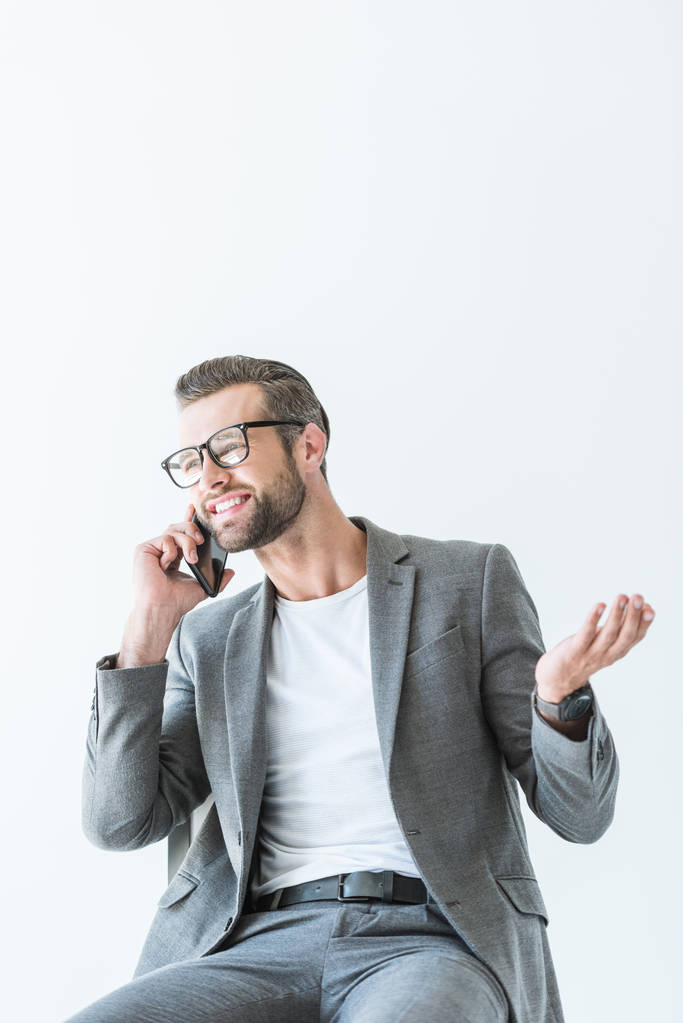 komea liikemies harmaassa puvussa elehtii ja puhuu älypuhelimella, eristetty valkoisella
 - Valokuva, kuva