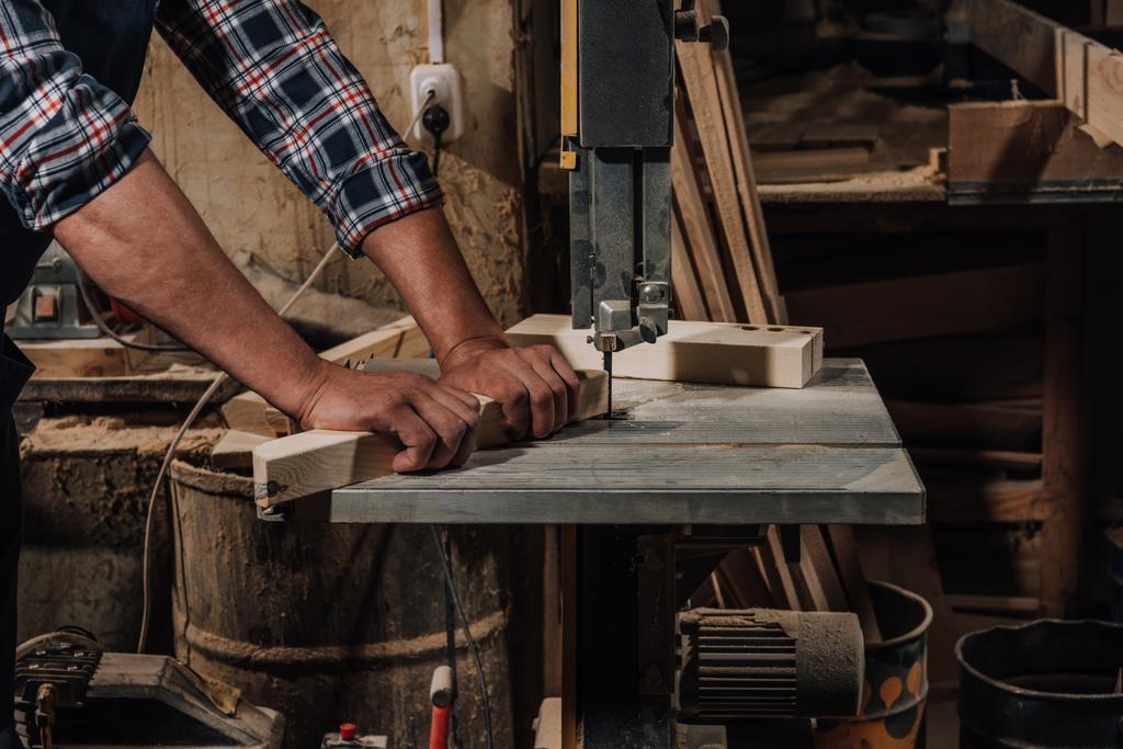 vista parcial del carpintero utilizando taladro eléctrico sobre madera en el taller
 - Foto, imagen