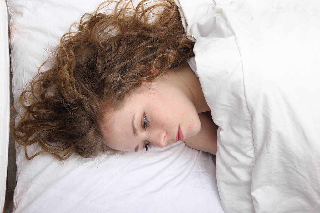Όμορφη νεαρή κοπέλα ξαπλωμένη στο κρεβάτι - Φωτογραφία, εικόνα