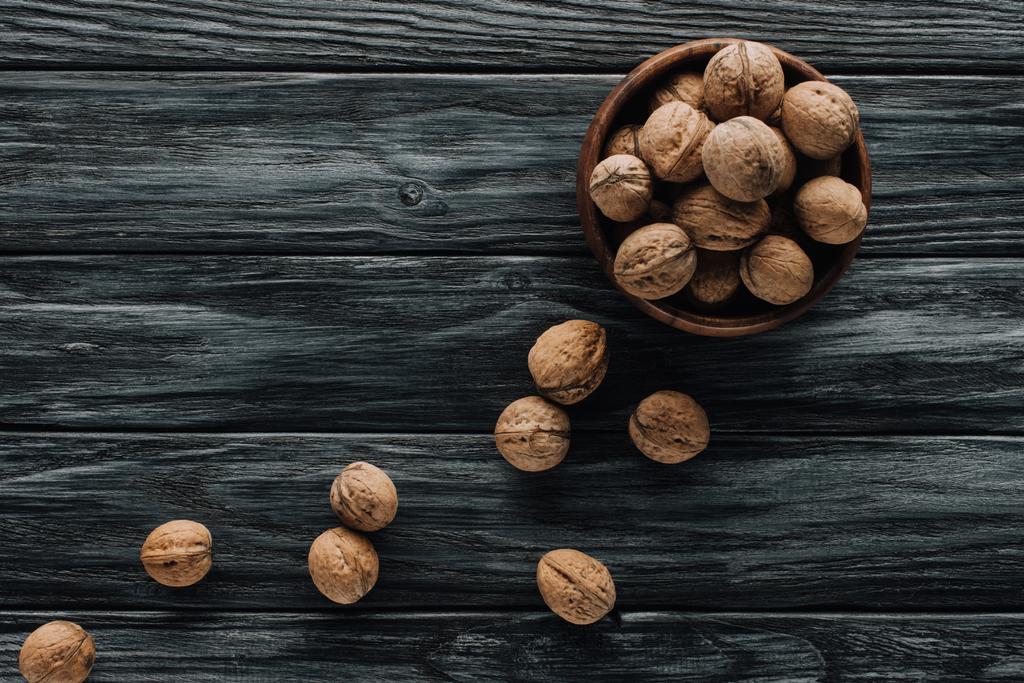 вкусные грецкие орехи в деревянной чаше на темной деревянной столешнице
 - Фото, изображение
