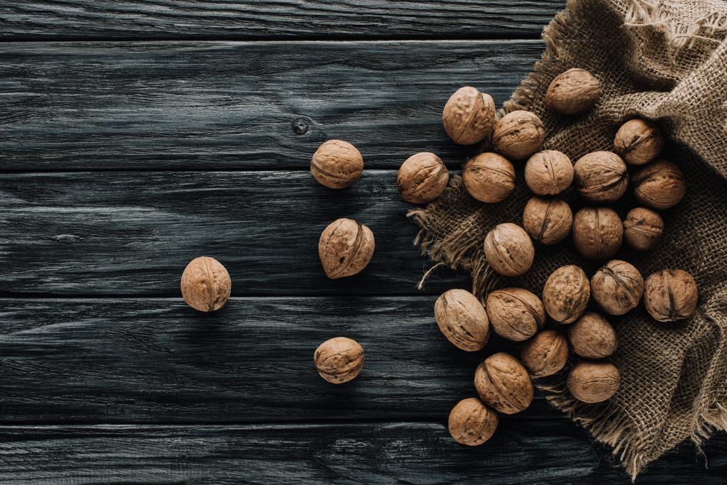  walnoten in nutshells met zak op donkere houten oppervlak  - Foto, afbeelding