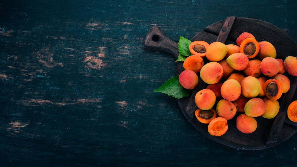 Fresh apricots with leaves On a black wooden background. Top view. Free space for your text. - Photo, Image