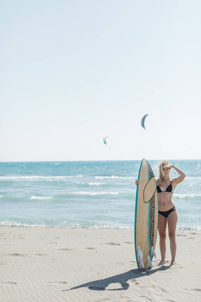 Портрет красивой молодой кавказской девушки, стоящей на пляже с доской для серфинга
. - Фото, изображение