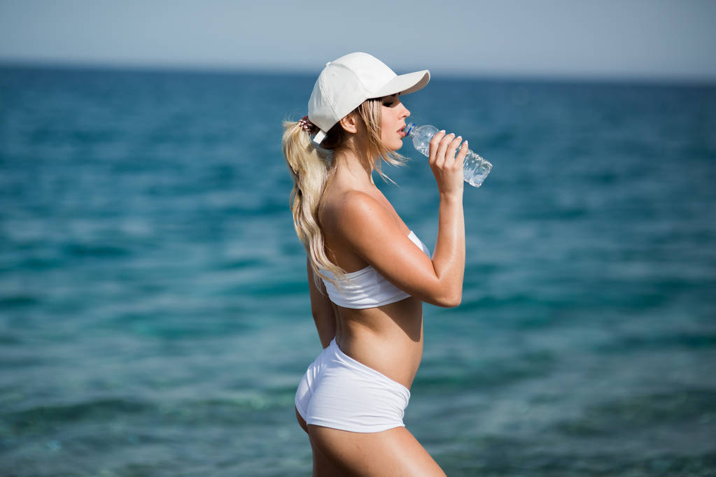 Belle athlète de fitness femme boire de l'eau après l'exercice sur la plage portrait en plein air
 - Photo, image
