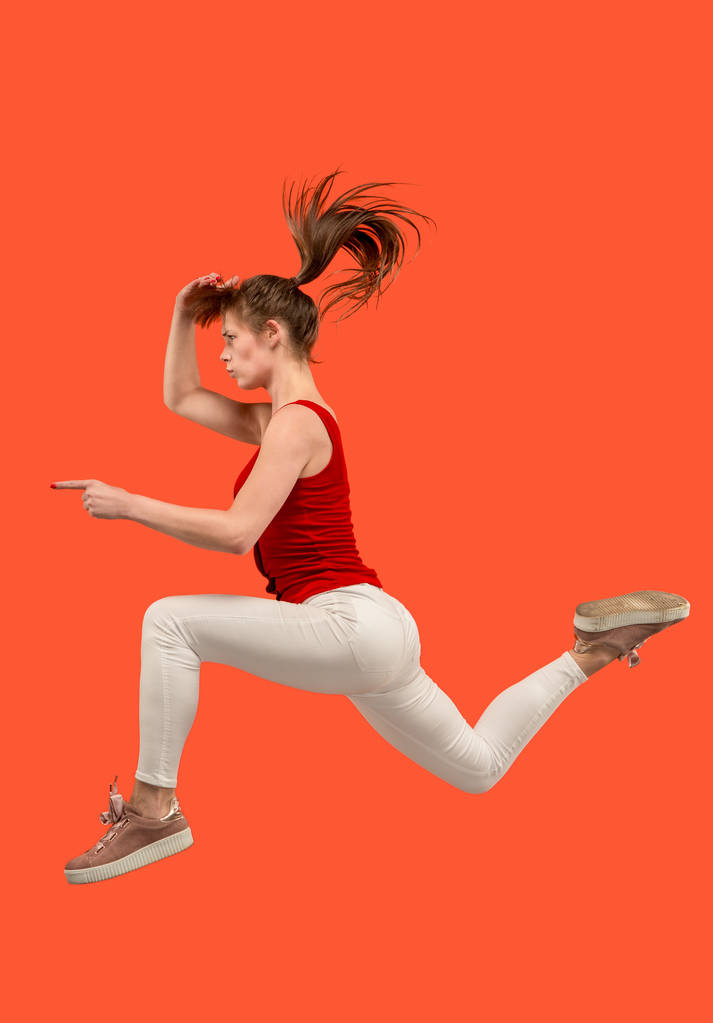 Liikkumisvapaus. Kaunis nuori nainen hyppää oranssia taustaa vasten
 - Valokuva, kuva
