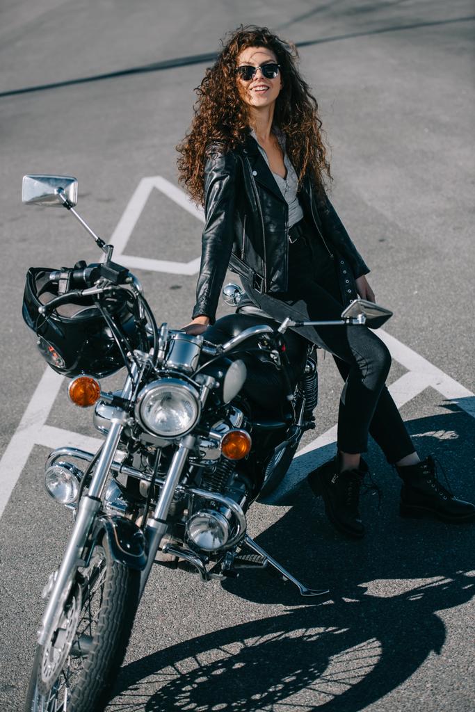 motociclista feminina feliz sentado na motocicleta clássica no estacionamento urbano
  - Foto, Imagem