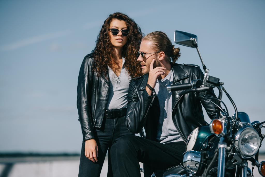 pareja de motociclistas en chaquetas de cuero sentados en la motocicleta clásica vintage
 - Foto, imagen