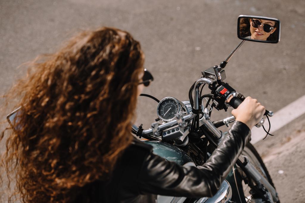 piękna dziewczyna kręcone siedzi na motocyklu na parking - Zdjęcie, obraz