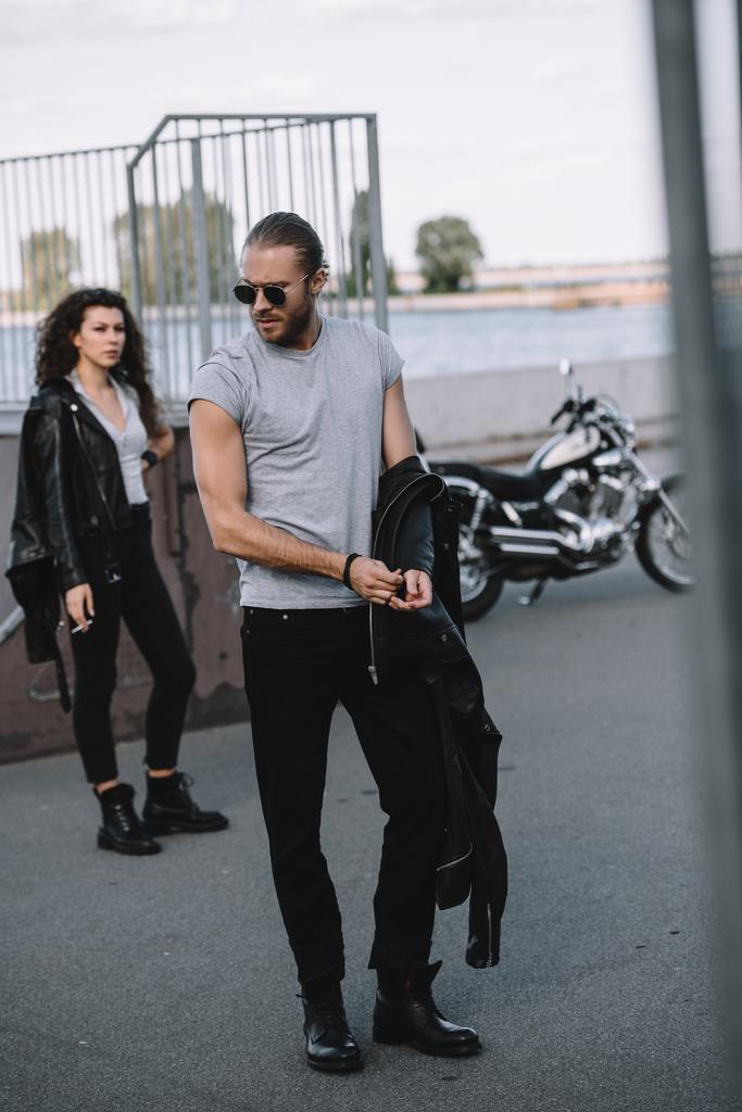 男と古典的なバイクの側に立っての黒い革のジャケットのガール フレンド  - 写真・画像