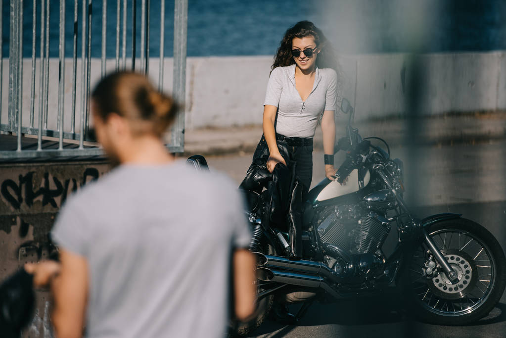 Selektiver Fokus des Motorradfahrers auf Freundin mit Oldtimer-Motorrad  - Foto, Bild