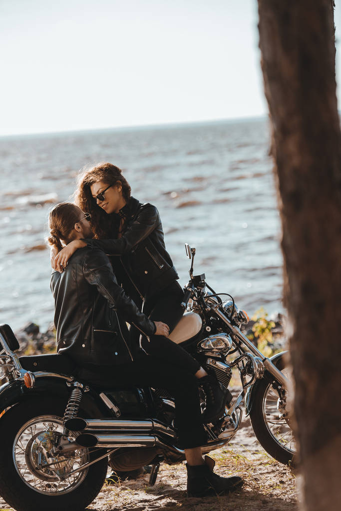 jovem casal abraçando na motocicleta clássica na costa
 - Foto, Imagem