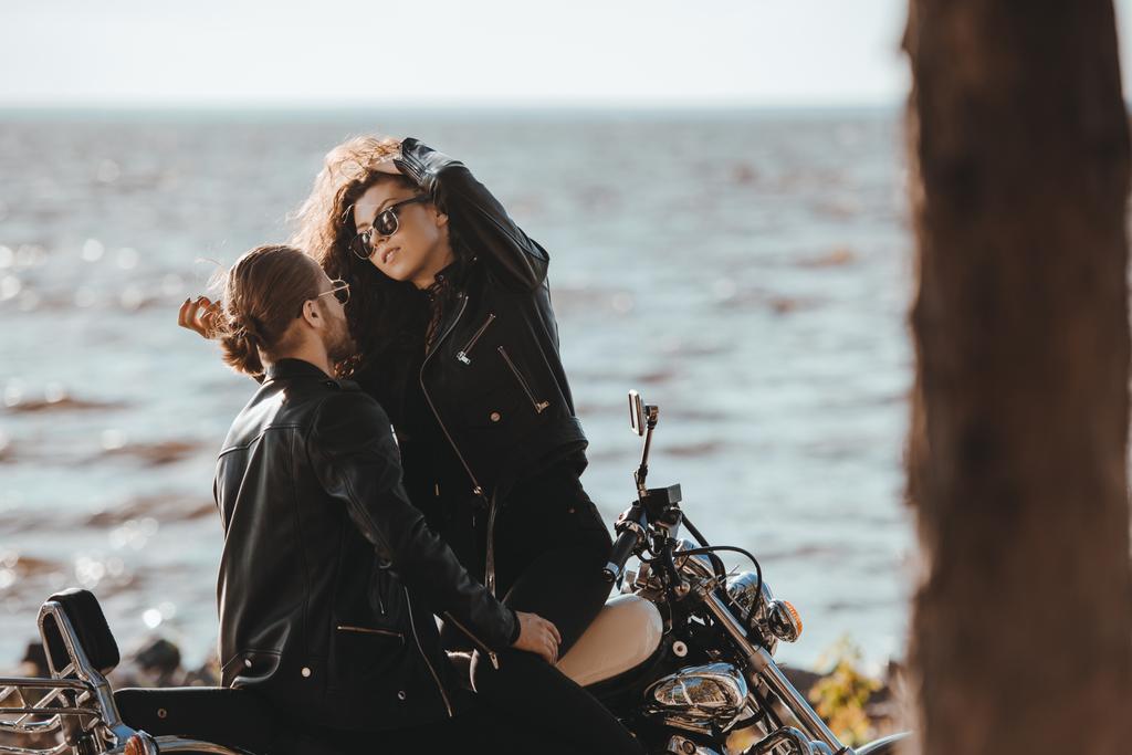 couple of bikers embracing on chopper motorcycle on seashore - Photo, Image