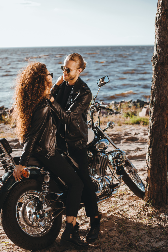 пара байкеров, обнимающихся на классическом мотоцикле на берегу моря
 - Фото, изображение