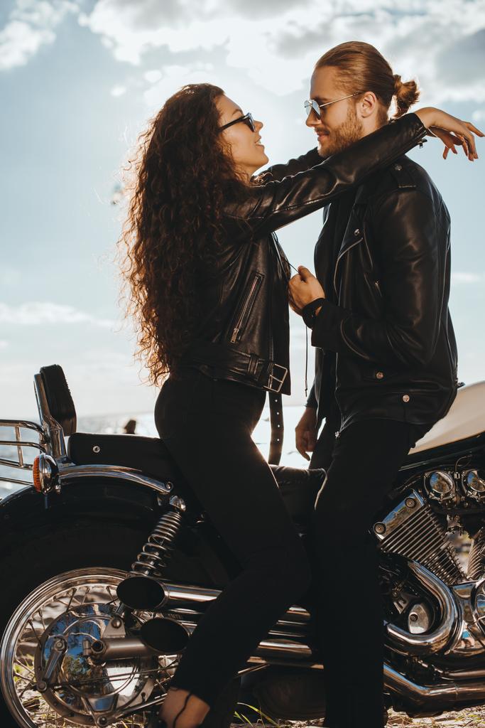 Couple in black leather jackets hugging on vintage motorbike - Photo, Image