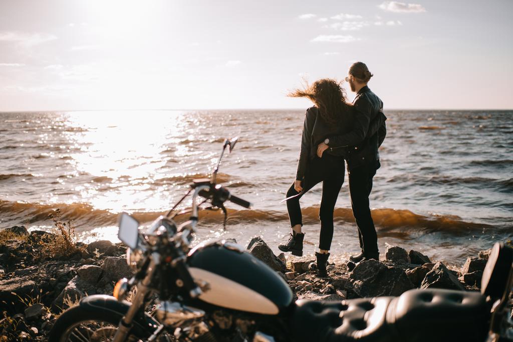 海とバイクを前景に夕日を見てカップルの選択と集中 ロイヤリティフリー写真 画像素材