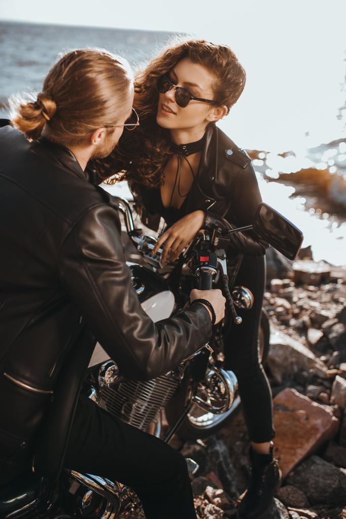 vriendin flirten met haar vriendje terwijl hij zittend op klassieke motorfiets - Foto, afbeelding