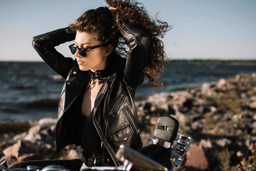hermosa chica rizada en gafas de sol sentado en la motocicleta
 - Foto, Imagen