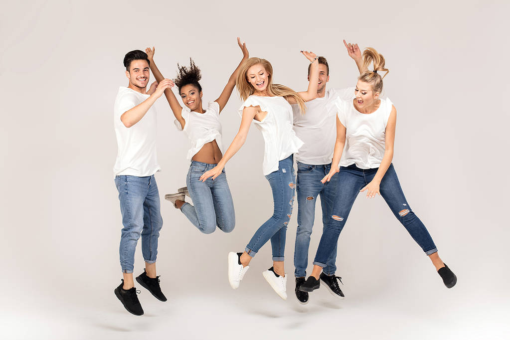 若者のグループ多民族魅力的な白いシャツを着て笑顔し、楽しんで、一緒にスタジオでジャンプ. - 写真・画像