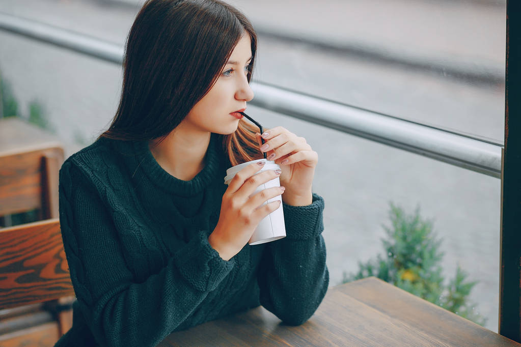 Meisje zit in het café op de tabel en drinken koffie - Foto, afbeelding