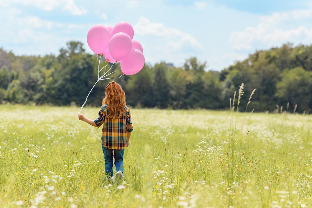 vue arrière de l'enfant avec des ballons roses marchant dans le champ d'été
 - Photo, image
