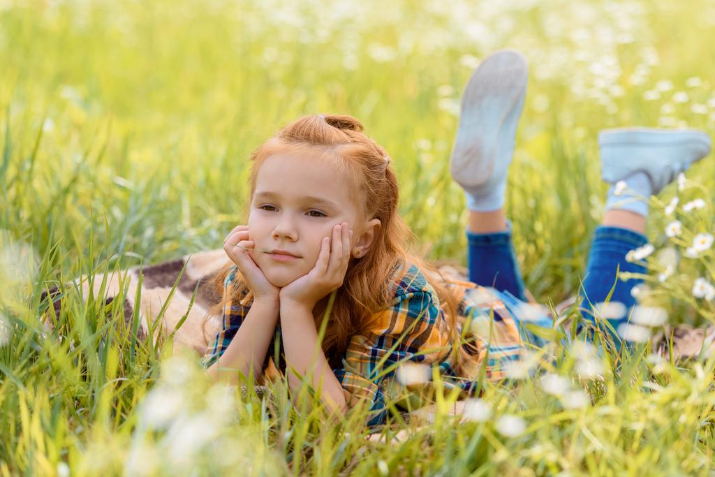 portrét zamyšlený dítě odpočívá na zelené trávě v louce - Fotografie, Obrázek