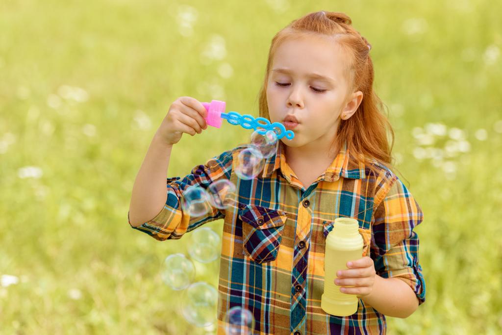 portrait d'enfant soufflant des bulles de savon dans la prairie
 - Photo, image