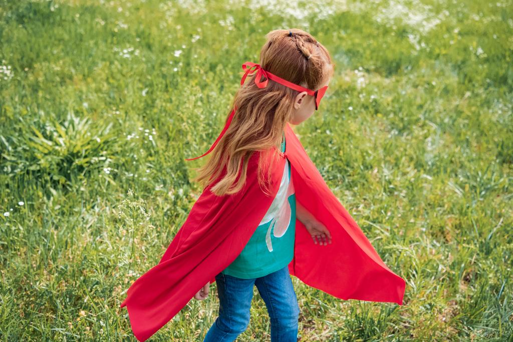 kis gyermek állandó nyári mezőben piros szuperhős-jelmez - Fotó, kép