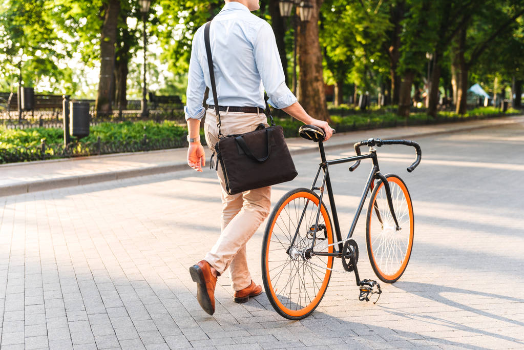 Bir bisiklet ile bir şehir sokak yürüyüş çanta ile genç bir adamın gömlekli resim kırpılmış - Fotoğraf, Görsel