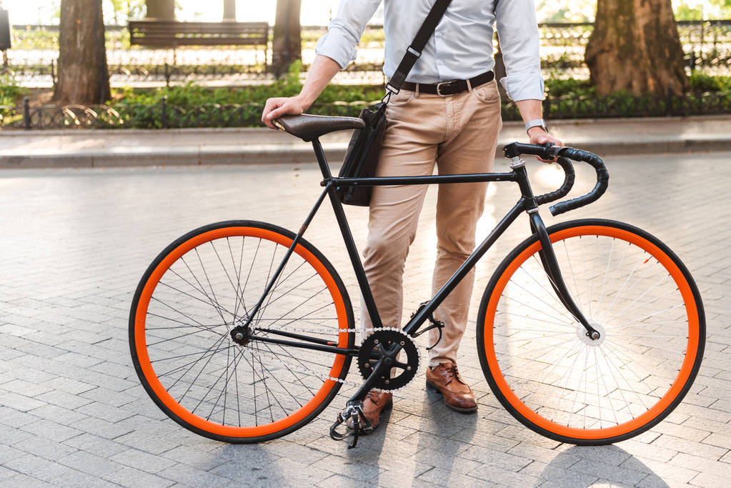 Levágott kép egy fiatal férfi ing, táska állandó egy biciklit, a város utca - Fotó, kép