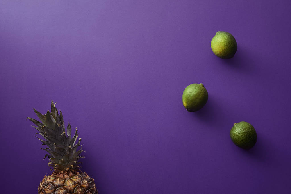 vue de dessus de l'ananas et des citrons verts sur la surface violette
 - Photo, image