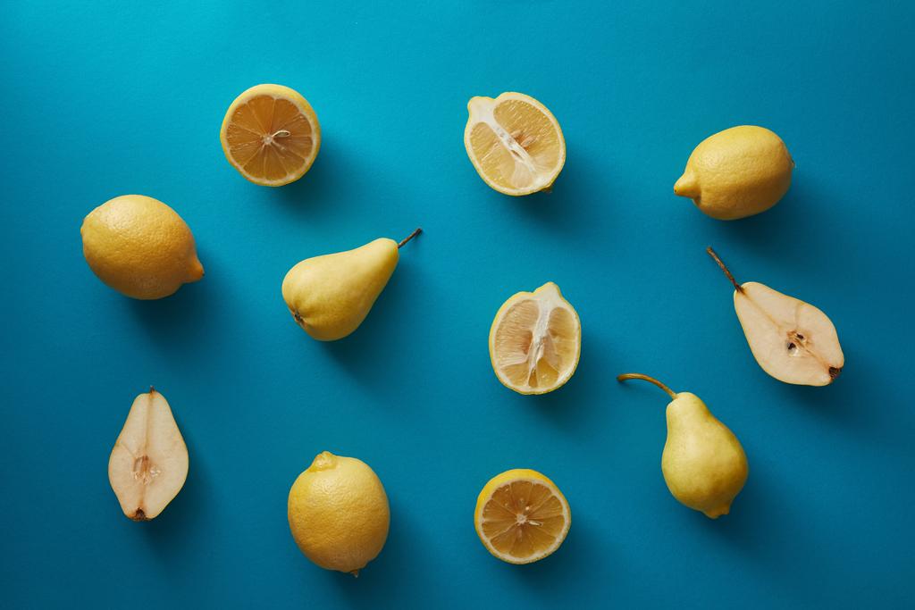 υπερυψωμένη θέα ώριμα αχλάδια και τα λεμόνια σε μπλε επιφάνεια  - Φωτογραφία, εικόνα