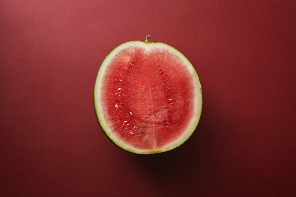 bovenaanzicht van de helft van watermeloen op rode oppervlak - Foto, afbeelding