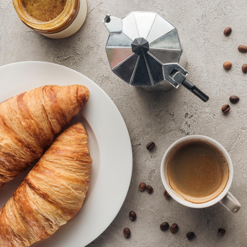 top view of cup of coffee with croissants and moka pot on concrete surface - Photo, Image
