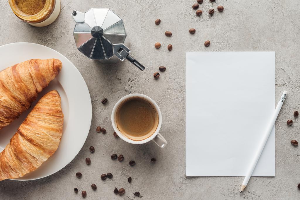 top view of cup of delicious coffee with croissants and blank paper on concrete surface - Photo, Image