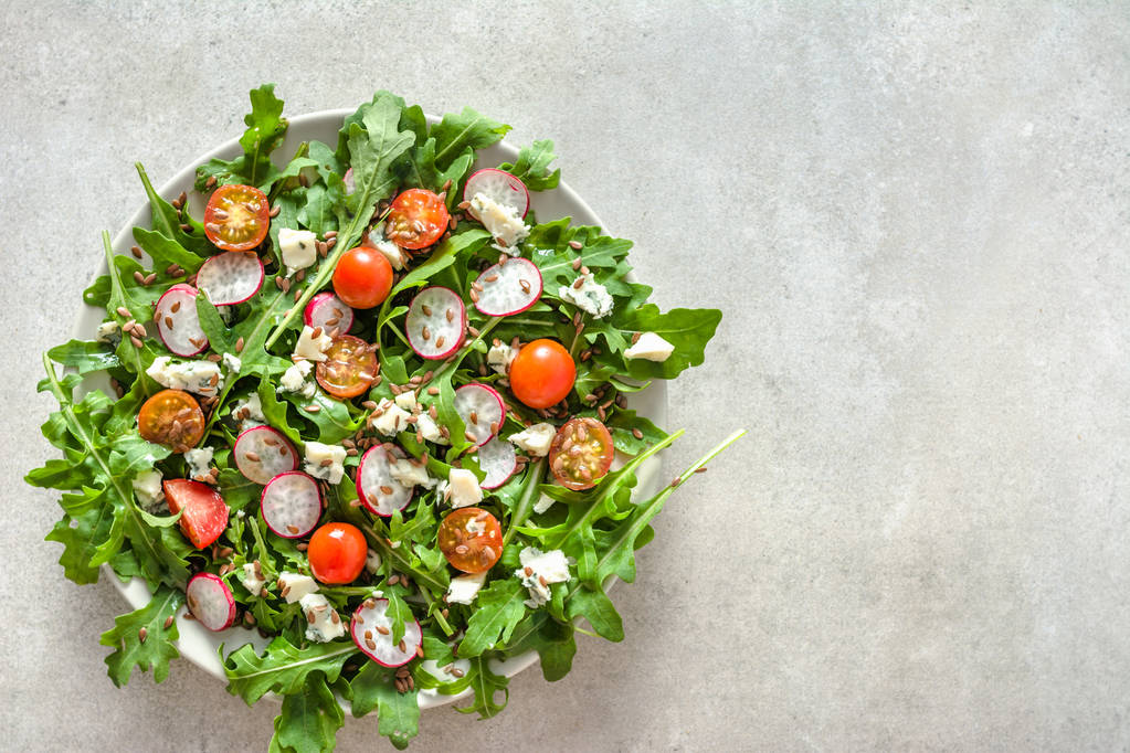 frischer Salat mit Rucola und Gemüse - Feta-Käse, Tomaten, Samen und Rettich. Bio-Gemüsekost, vegetarisches Ernährungskonzept. - Foto, Bild