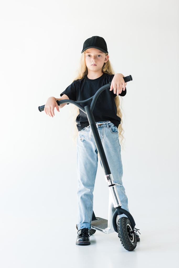 vista a tutta lunghezza del bambino con lunghi capelli ricci in piedi con scooter e guardando la fotocamera isolata su bianco
 - Foto, immagini