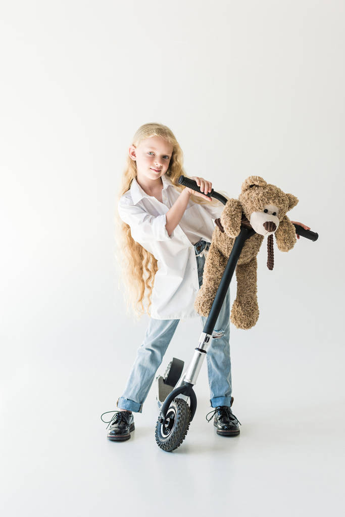 scooter ve oyuncak ayı, uzun kıvırcık saç ayakta beyaz kameraya gülümseyen sevimli çocukla   - Fotoğraf, Görsel