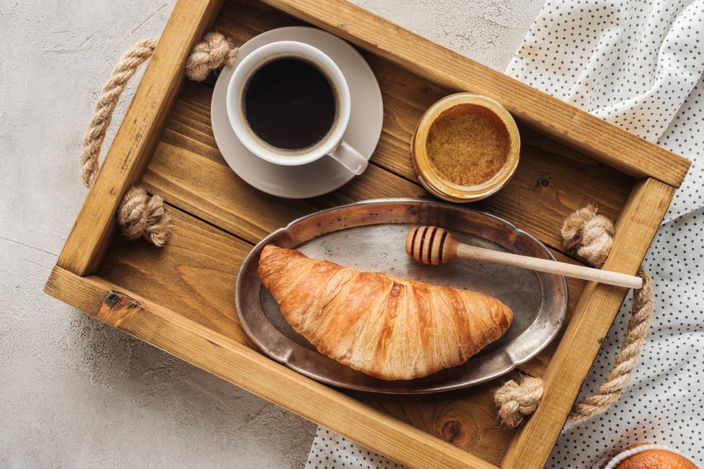 vue de dessus de tasse de café avec croissant et miel sur plateau sur la surface du béton
 - Photo, image