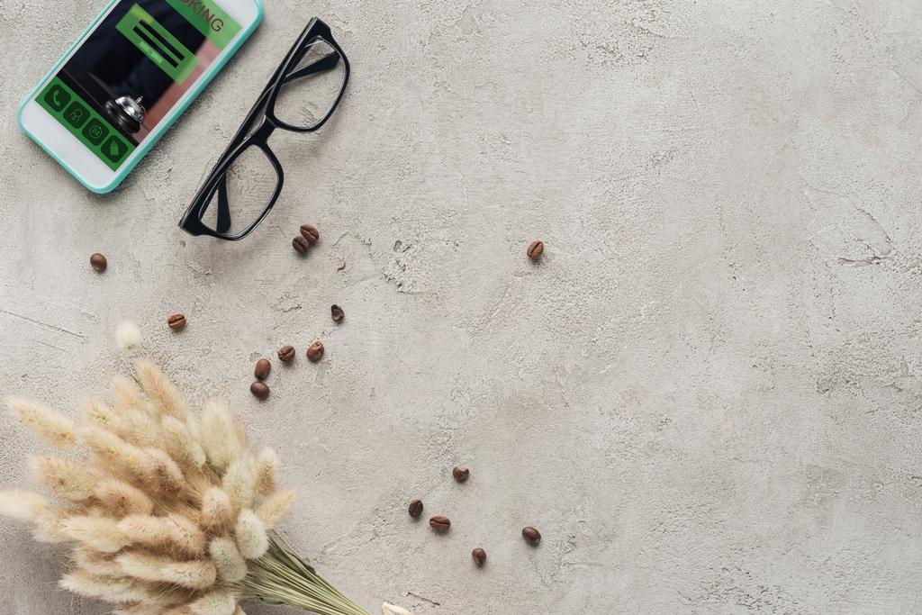 a képernyő-val szemüveg, kiömlött kávé bab és lagurus ovatus csokor a betonfelület smartphone app foglalás felülnézet - Fotó, kép