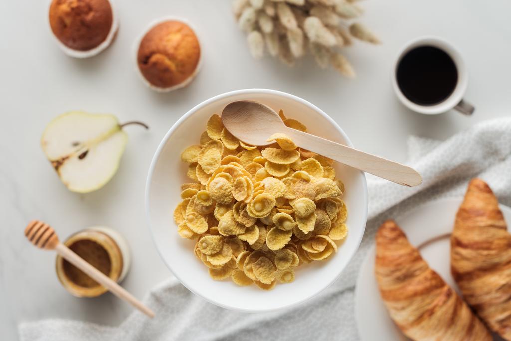 vue du dessus du bol de flocons de maïs avec délicieux café, croissants et muffins sur blanc
 - Photo, image