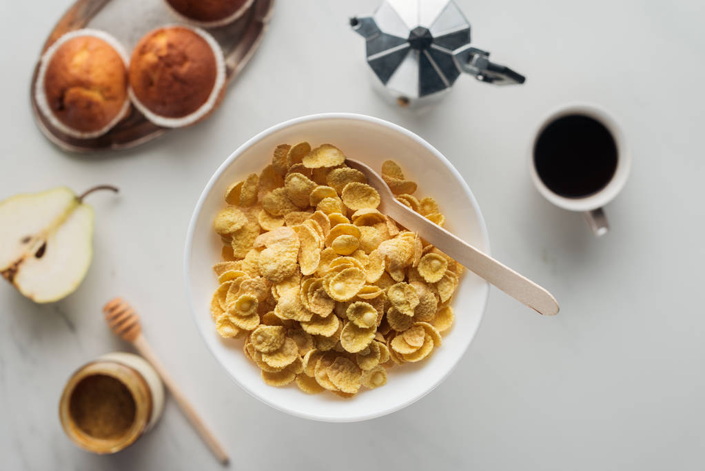 vista superior del tazón de cereal seco con delicioso café y magdalenas en blanco
 - Foto, imagen
