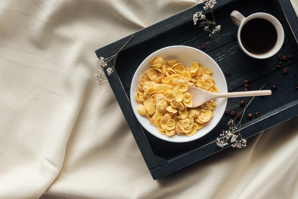 верхний вид на миску хлопьев завтрак с чашкой кофе на подносе на бежевой ткани, завтрак в кровать концепции
 - Фото, изображение