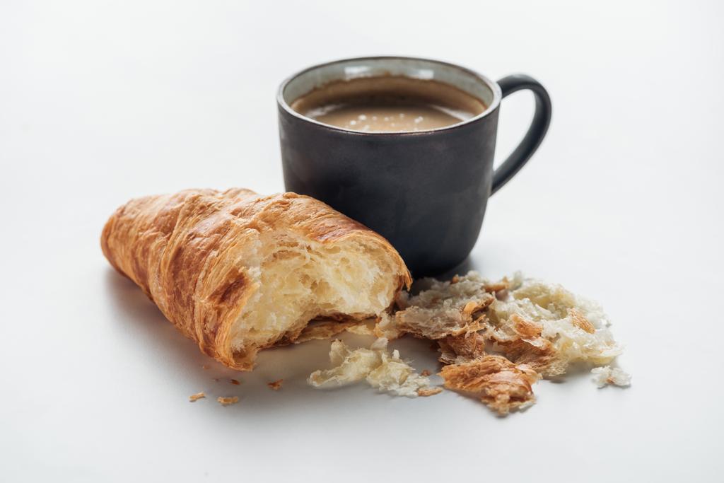 primer plano de taza de café y croissant mordido en blanco
 - Foto, imagen