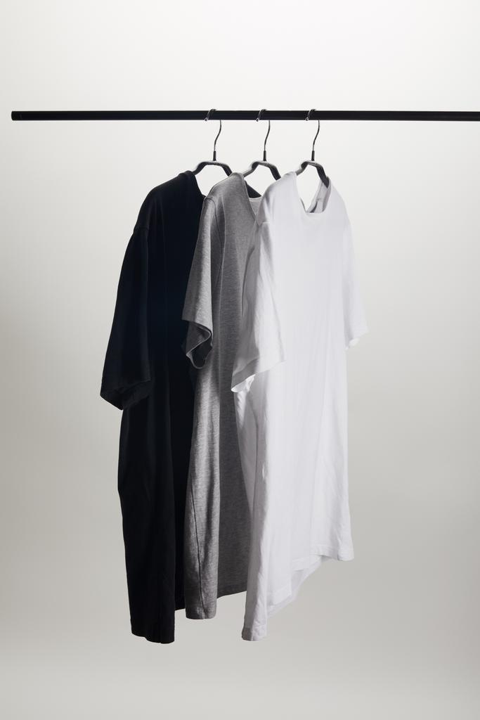 camisas negras, grises y blancas en perchas aisladas en blanco
 - Foto, Imagen