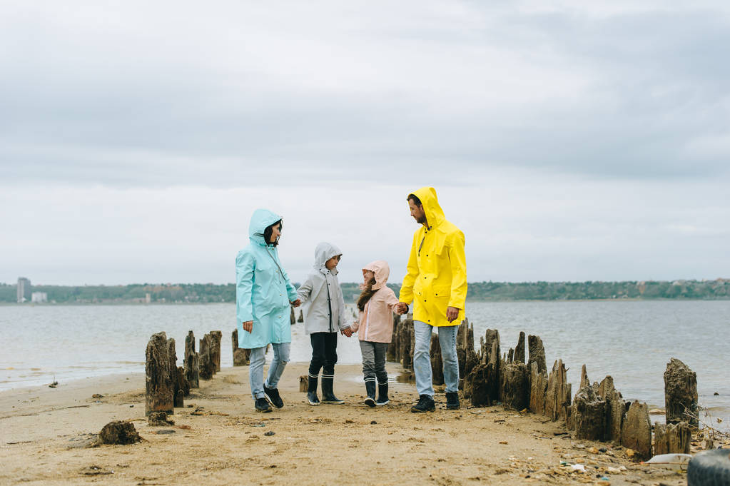 Bellissimo ritratto di famiglia vestito con impermeabile colorato vicino al lago
 - Foto, immagini