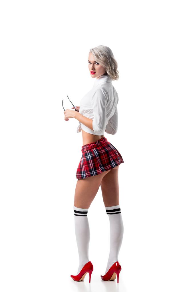 боковой вид сексапильной молодой женщины в короткой школьной юбке и коленных очках, позирующей в белом
 - Фото, изображение